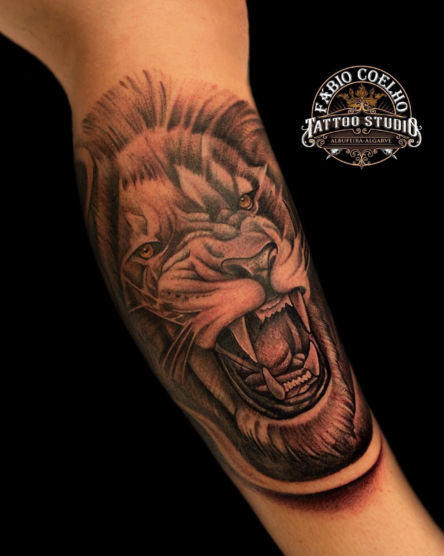 Roaring lion in black and grey on the forearm