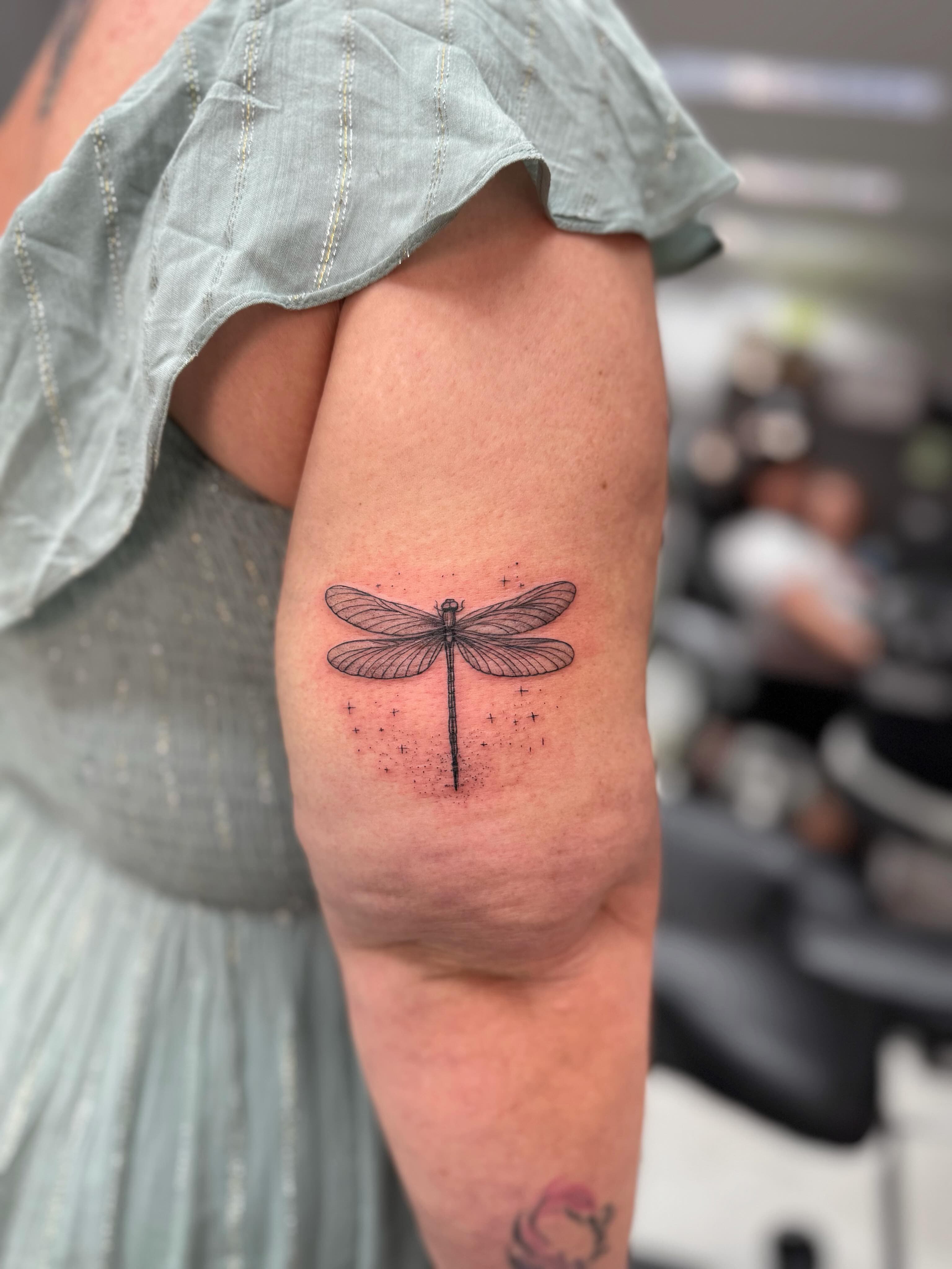 Fine line dragonfly on the arm